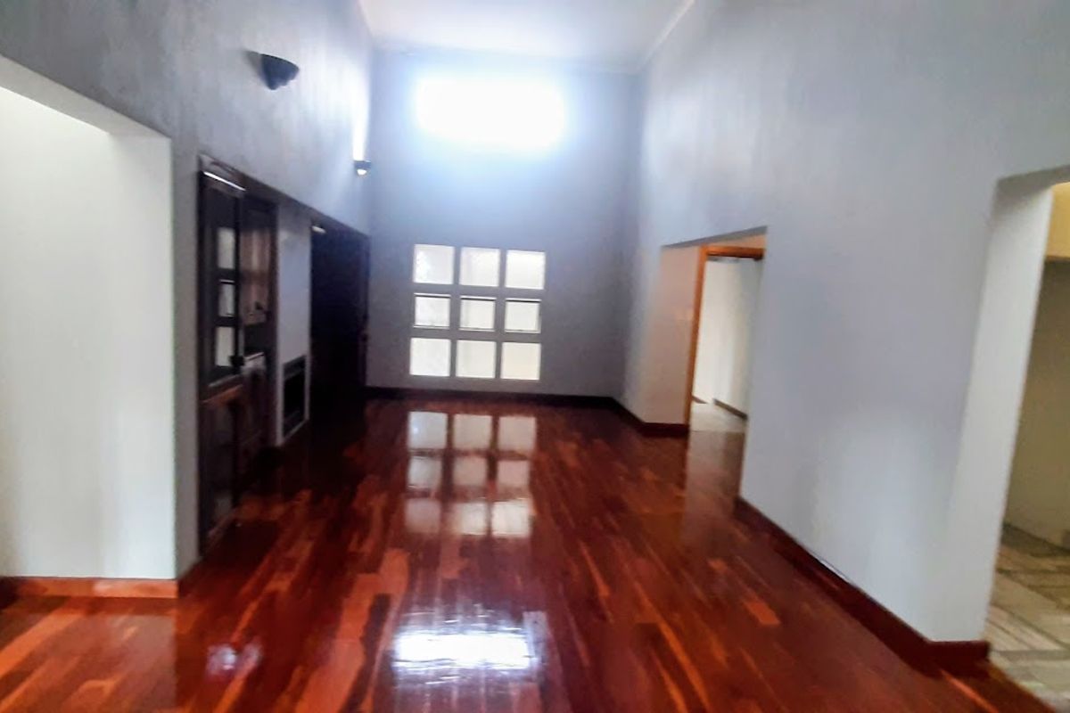 Spacious living area featuring polished hardwood flooring, high ceilings with natural light, and a unique brick pillar detail.