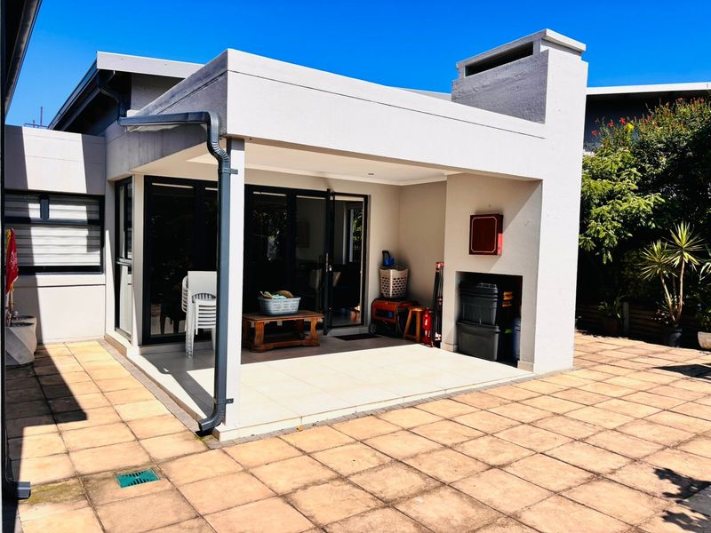 Covered patio area featuring a built-in braai, tiled flooring, and direct access to the interior through sliding doors.
