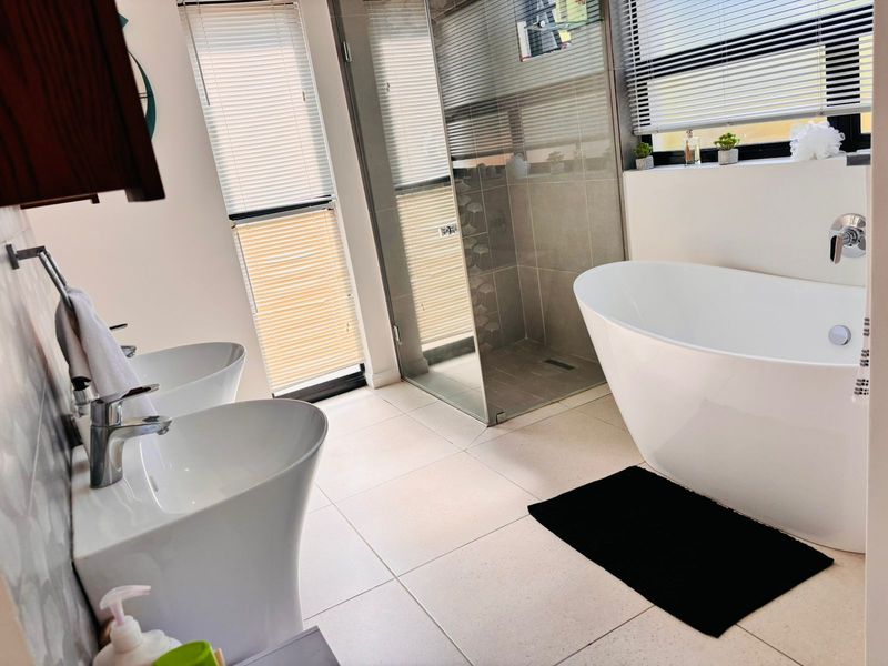 Modern bathroom featuring a sleek freestanding bathtub, a spacious walk-in shower, and dual pedestal sinks with contemporary chrome fixtures.