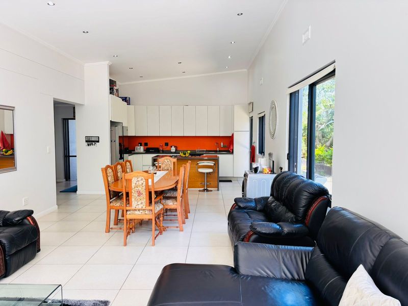 Spacious open-plan living and dining area featuring a modern kitchen with island, tiled floors, and large sliding doors providing natural light.