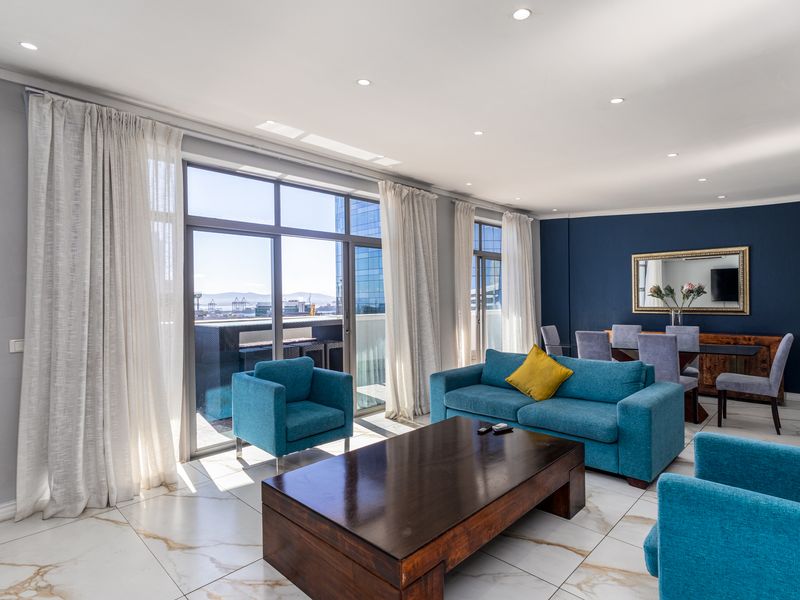 Spacious open-plan living and dining area featuring large format marble-look floor tiles, recessed downlights, and floor-to-ceiling sliding glass doors leading to the balcony.