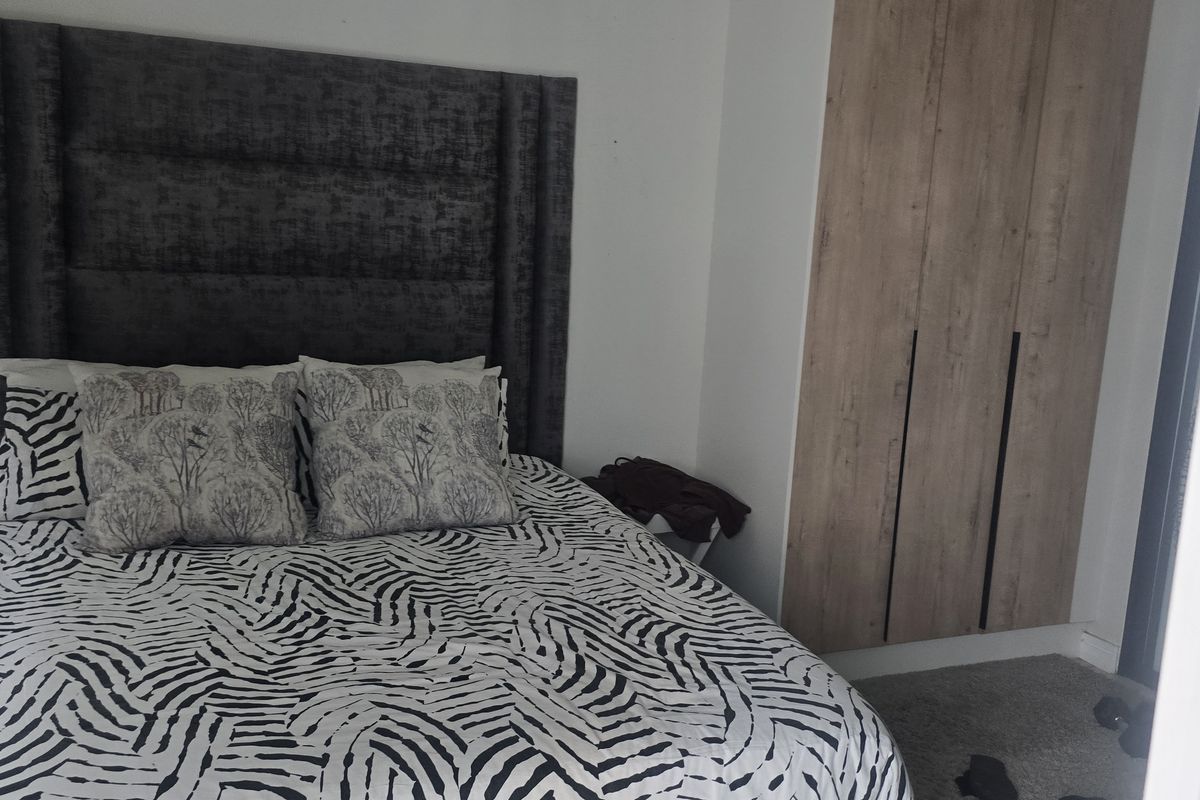 A well-maintained bedroom featuring built-in wooden cabinetry and a modern upholstered headboard, offering a clean and functional living space.