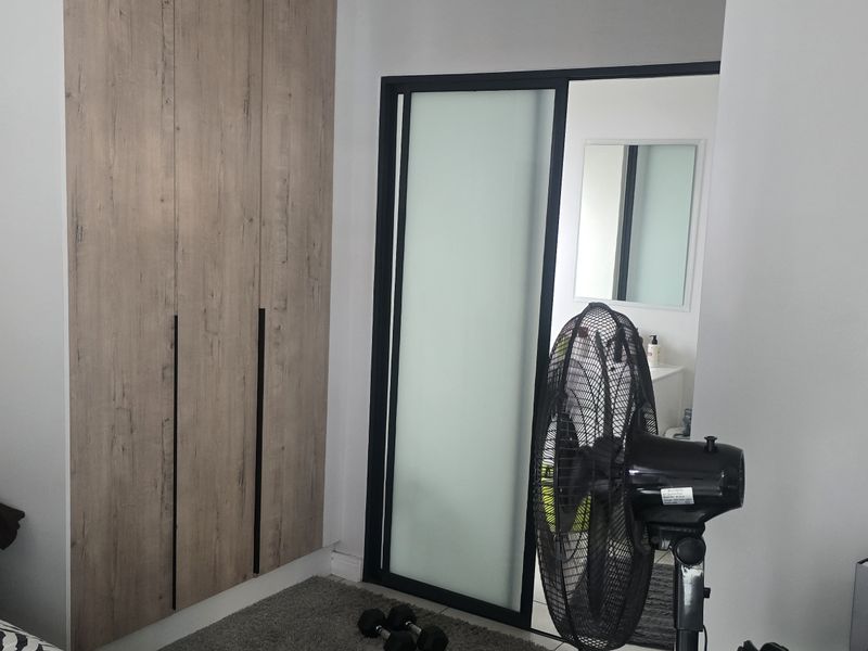 A bedroom featuring modern wood-look built-in cabinetry and a sliding door leading to an en-suite bathroom.
