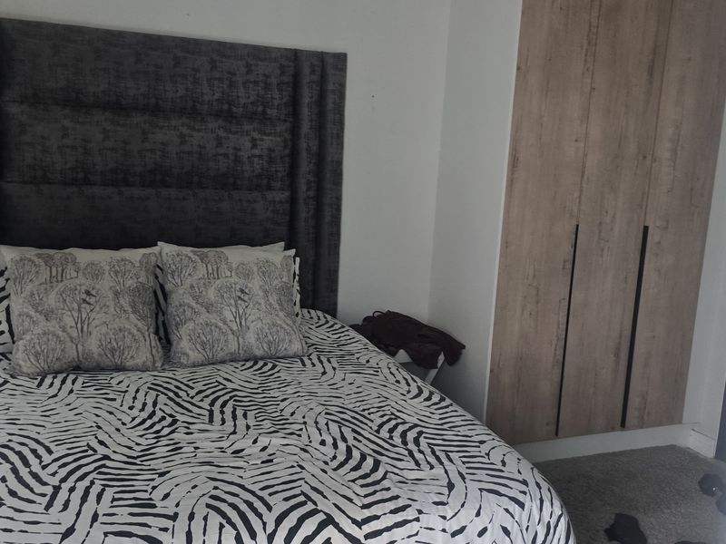 A well-maintained bedroom featuring built-in wooden cabinetry and a modern upholstered headboard, offering a clean and functional living space.