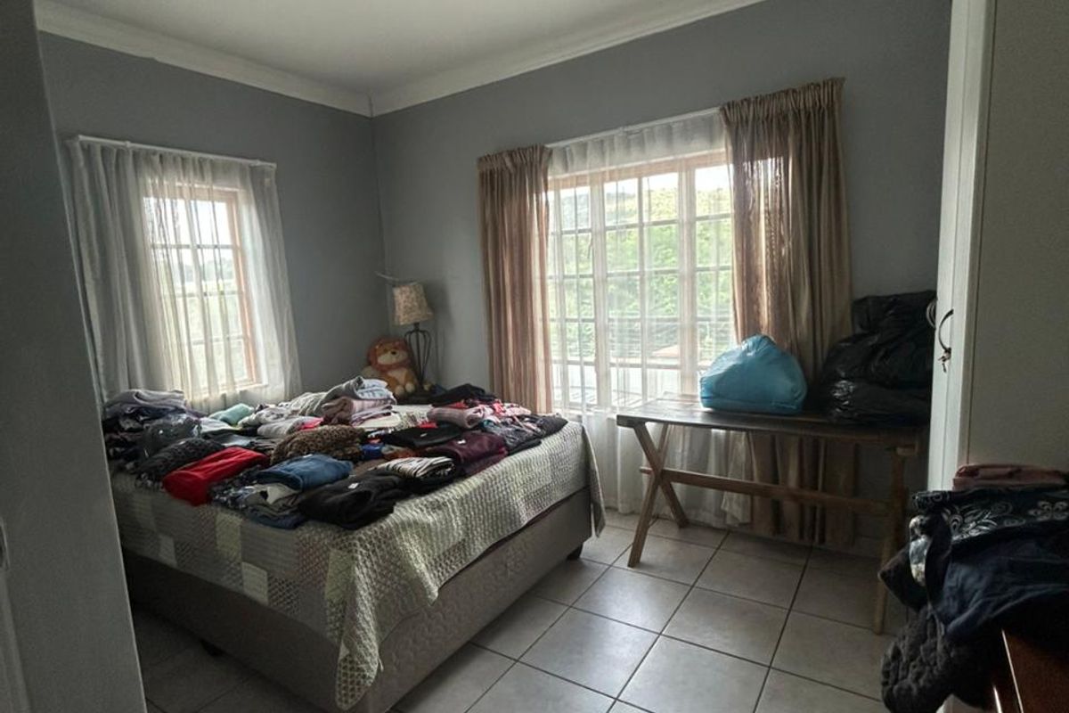 A bedroom featuring tiled flooring, recessed ceiling lighting, and dual windows with curtain tracks, offering a functional space with natural light.