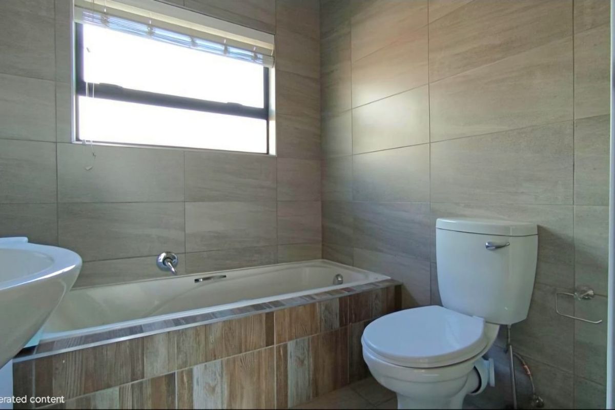 A modern bathroom featuring neutral wall tiling, a built-in bathtub with wood-look tile surround, a standard toilet, and a window for natural light.