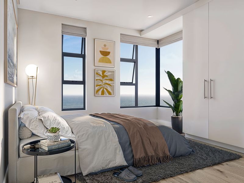 Modern bedroom featuring built-in wardrobes, timber flooring, and large windows offering expansive ocean views.