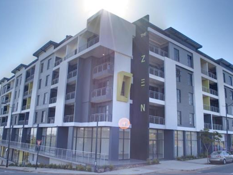 Modern multi-story apartment building exterior featuring contemporary architectural design, private balconies, and ground-floor commercial or retail frontage.
