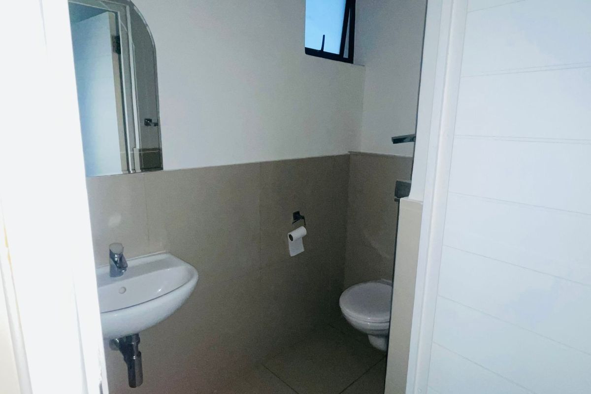 A compact guest bathroom featuring a wall-mounted basin, toilet, and neutral wall tiling.