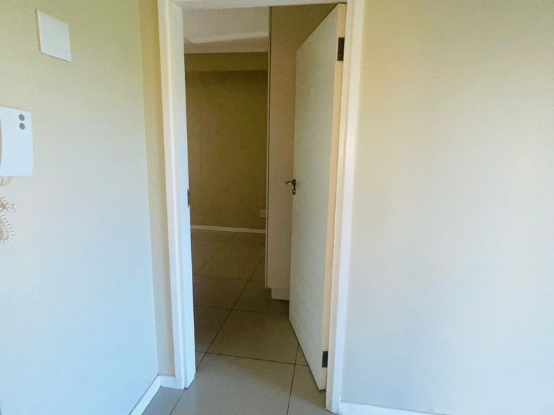 A view through an open doorway into an adjacent room, featuring neutral wall finishes and tiled flooring throughout the apartment space.