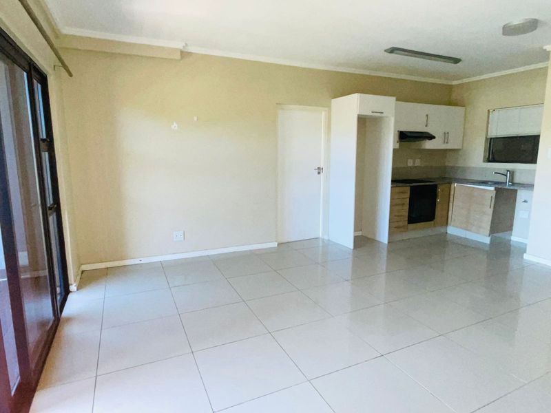 Open plan living area featuring tiled flooring and a compact kitchen with built-in cabinetry, oven, and extractor fan.