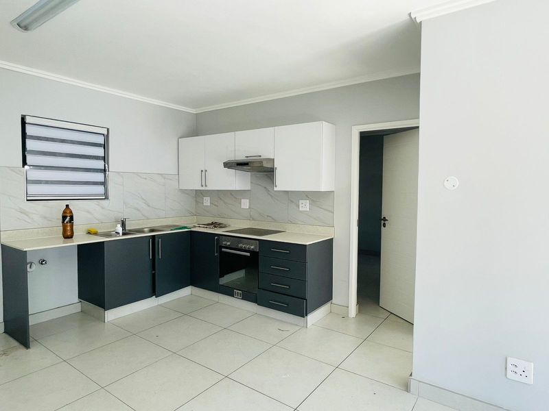 Modern kitchen featuring two-tone cabinetry, stone-look backsplash, built-in oven, hob, and extractor fan with tiled flooring.