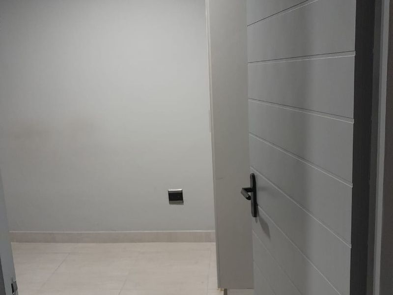 A view into a clean, empty room featuring neutral tiled flooring, modern grey painted walls, and a contemporary horizontal-panel interior door.