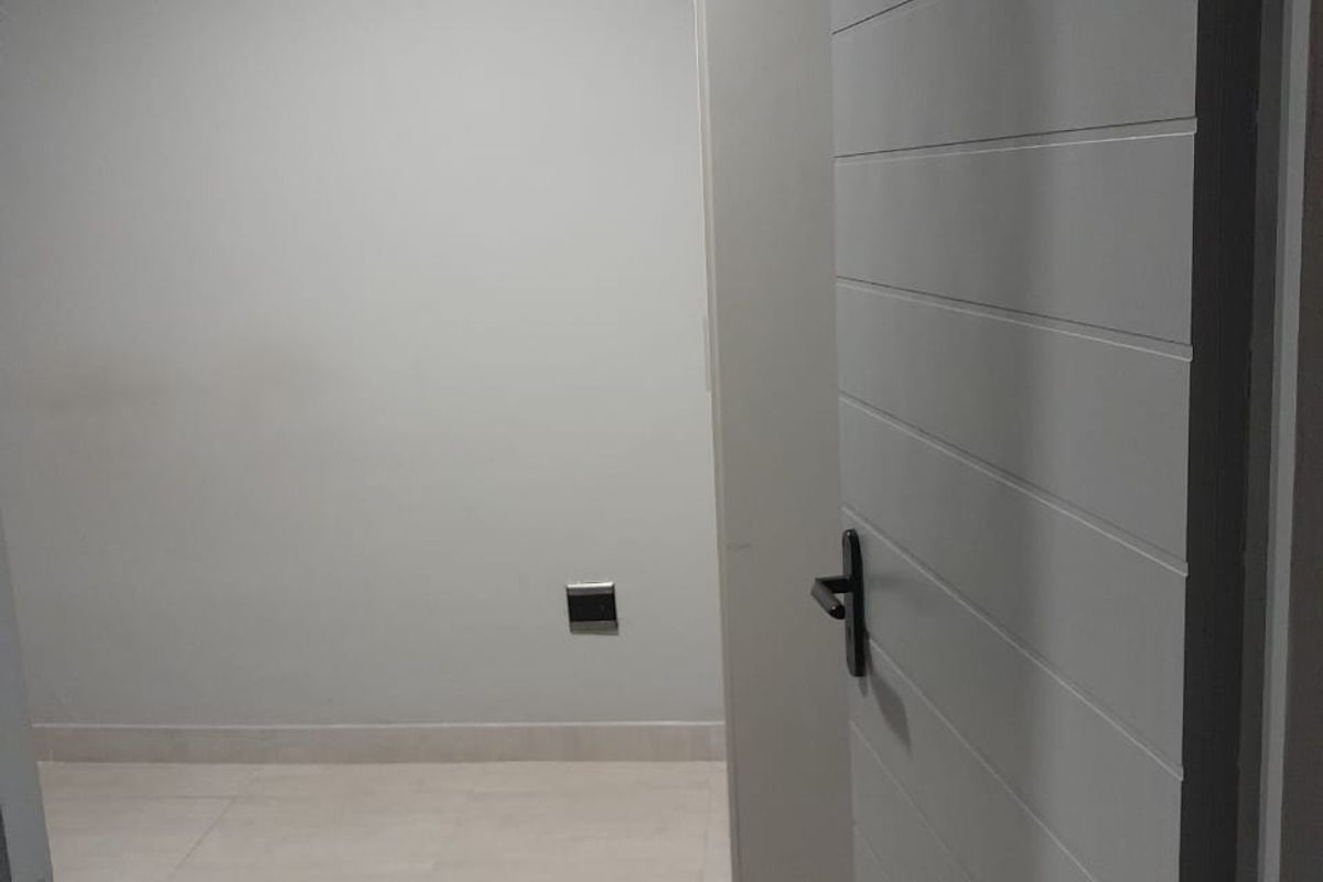 A view into a clean, empty room featuring neutral tiled flooring, modern grey painted walls, and a contemporary horizontal-panel interior door.