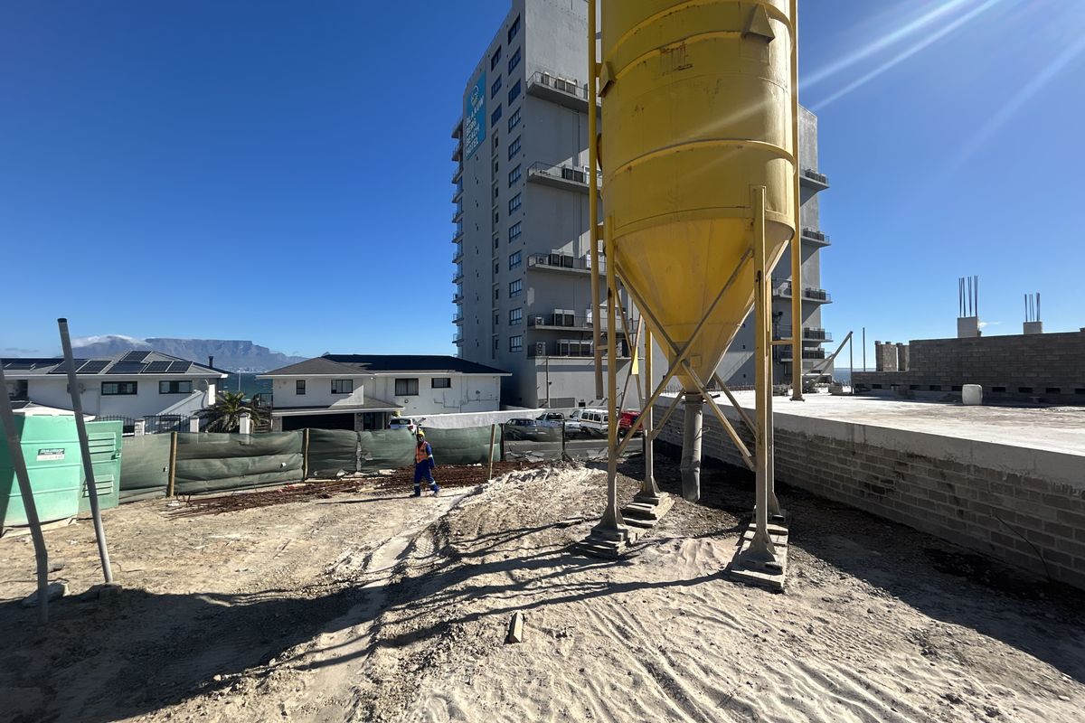 An active construction site featuring a large industrial silo, exposed brickwork, and ongoing development work in a coastal urban setting.