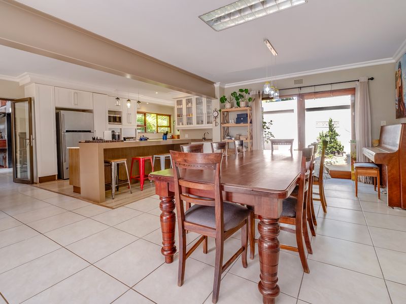 Spacious open-plan kitchen and dining area featuring tiled floors, a central kitchen island, and direct access to the outdoor space through sliding glass doors.