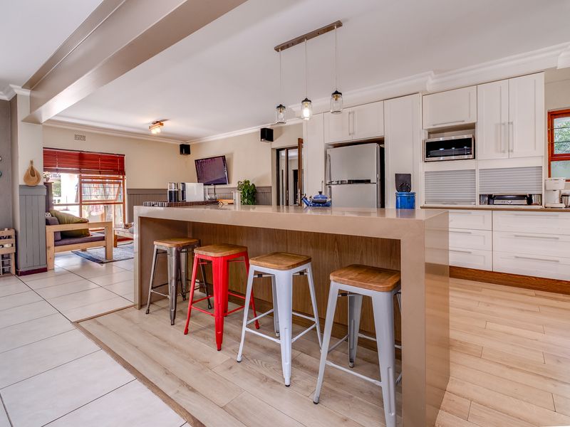 Spacious open-plan kitchen featuring a large central island, modern cabinetry, built-in appliances, and a seamless transition between tiled and laminate flooring areas.