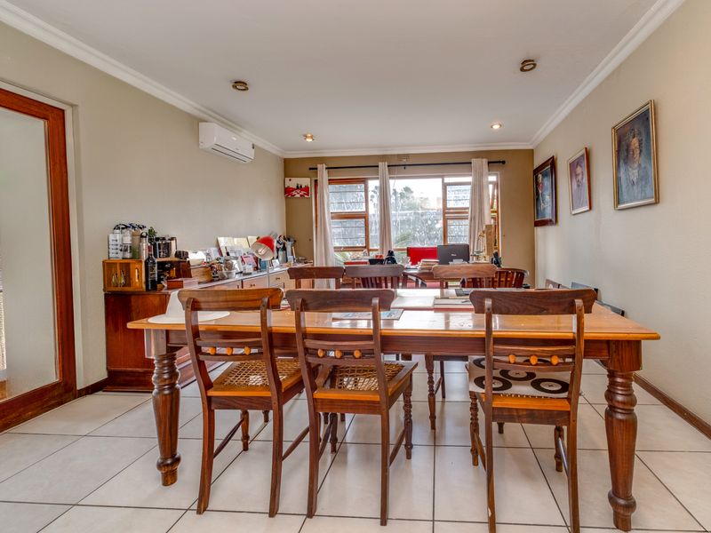 A spacious dining room featuring tiled flooring, recessed lighting, a split-system air conditioner, and large windows providing natural light.