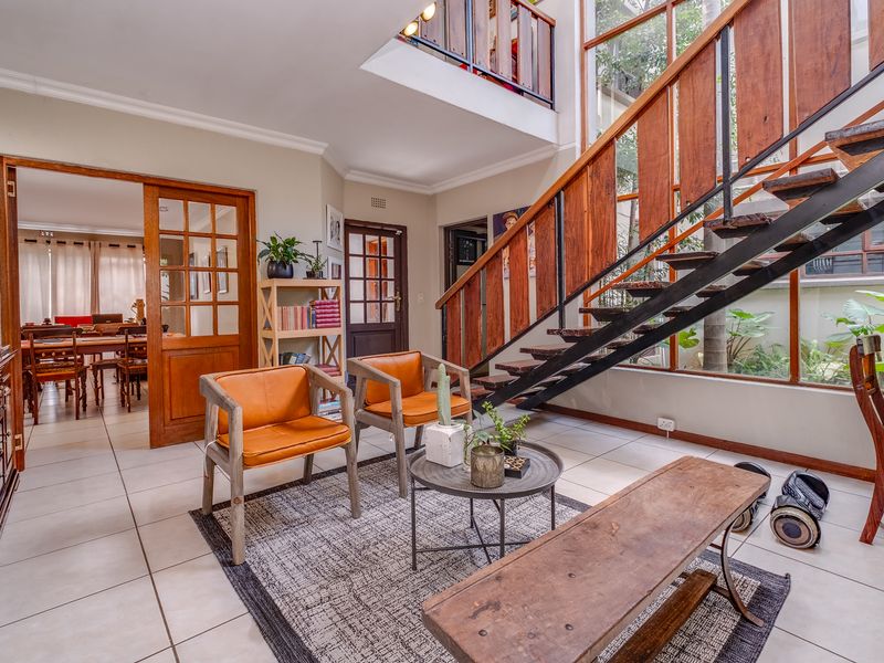 Spacious living area featuring a striking open staircase with wooden treads, double-height windows, and elegant french doors leading to an adjacent room.