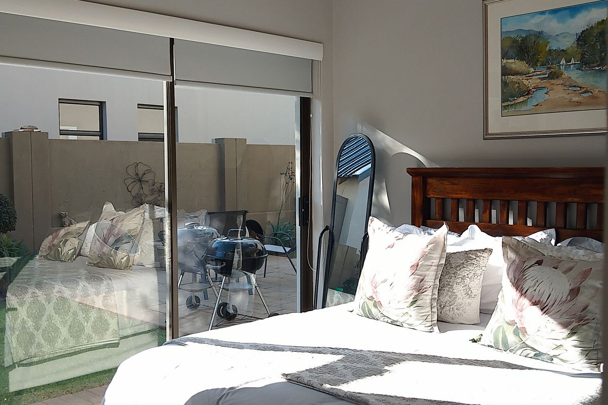A well-maintained bedroom featuring a split-system air conditioner and large sliding glass doors providing direct access to a paved patio area.