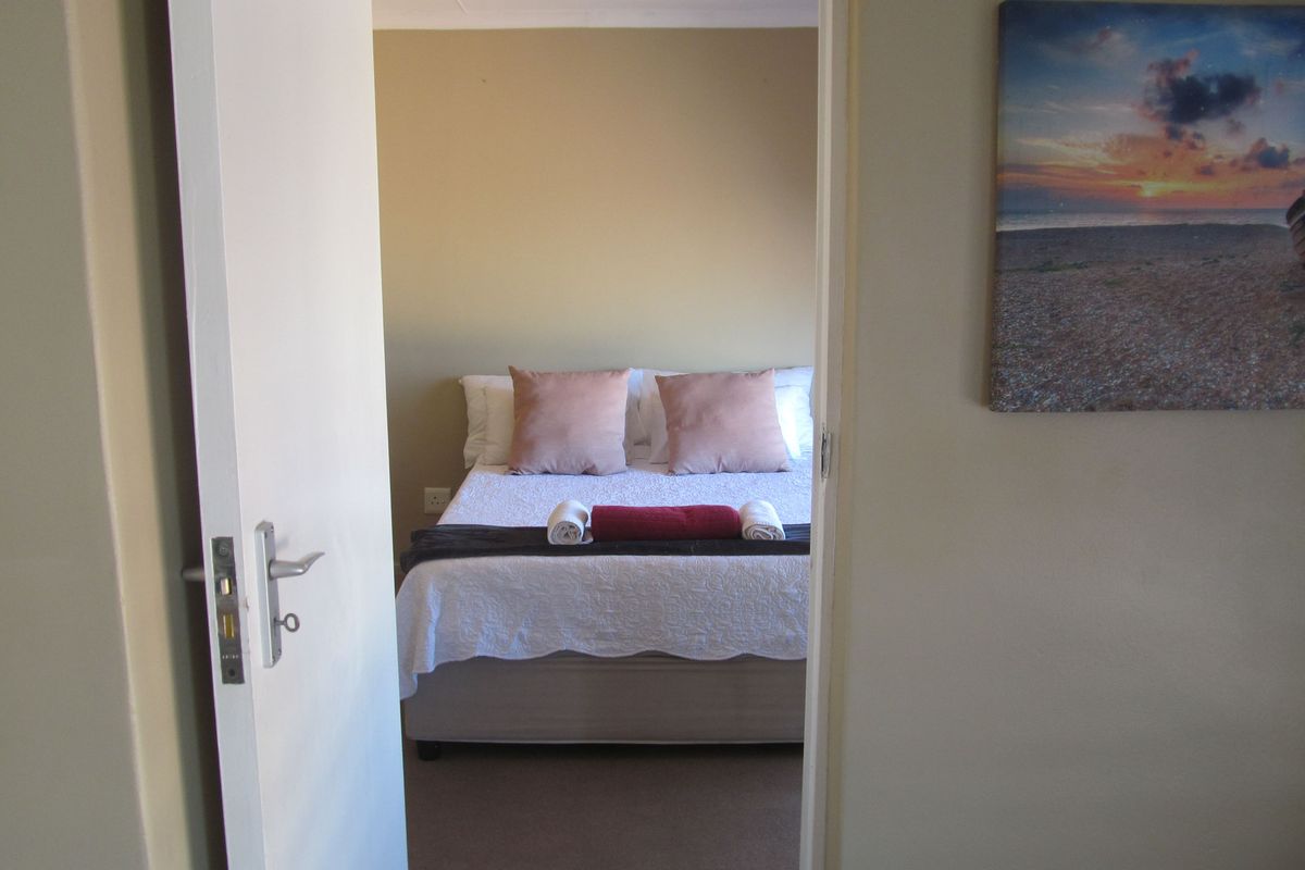 A view through a doorway into a bedroom featuring neutral wall tones and carpeted flooring.