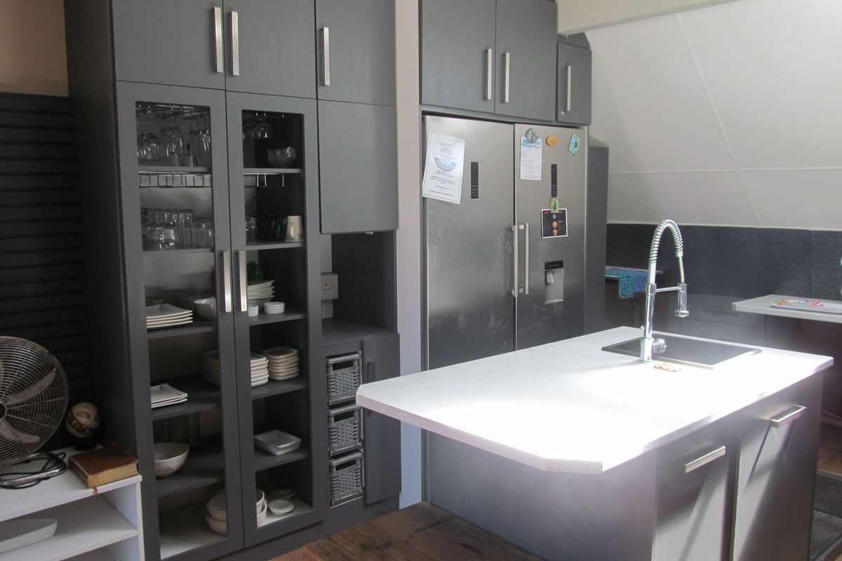 Modern kitchen featuring dark grey cabinetry, a central island with a built-in sink, and ample storage space.