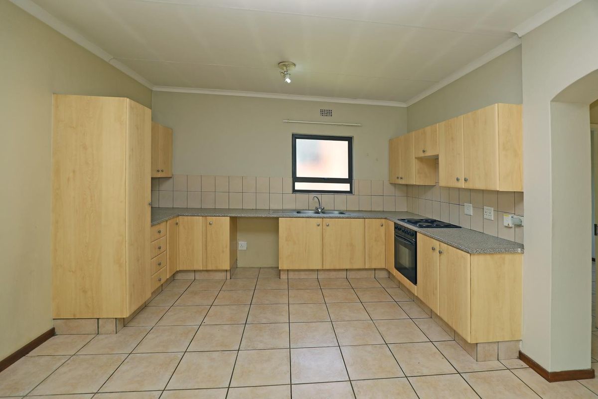 A functional kitchen featuring light wood-finish cabinetry, granite-look countertops, tiled flooring, and a built-in oven with a hob.