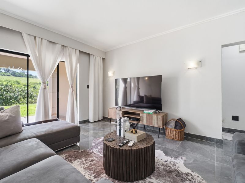 A bright and modern living room featuring large sliding glass doors that open to an outdoor area, complemented by sleek tiled flooring.