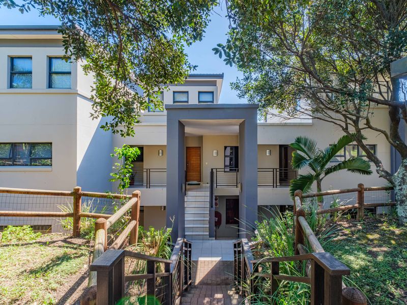 Front elevation of the apartment complex featuring a paved entrance walkway, tiled staircase, and modern architectural design with timber accents.