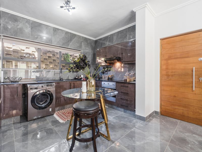 Modern kitchen featuring high-gloss cabinetry, stone tile finishes, integrated appliances, and a sleek, contemporary design with a functional layout.