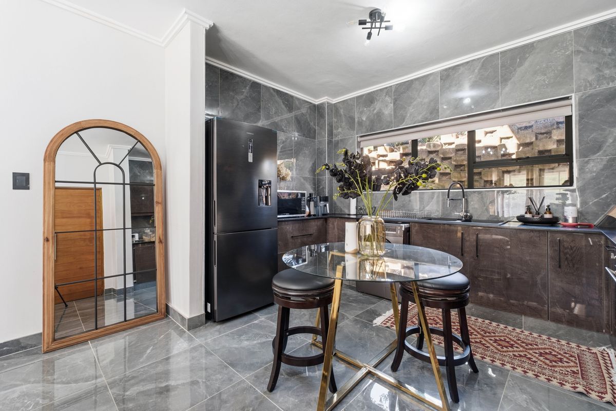 Modern kitchen featuring high-gloss cabinetry, marble-look wall and floor tiles, and a sleek undermount sink with a contemporary mixer tap.