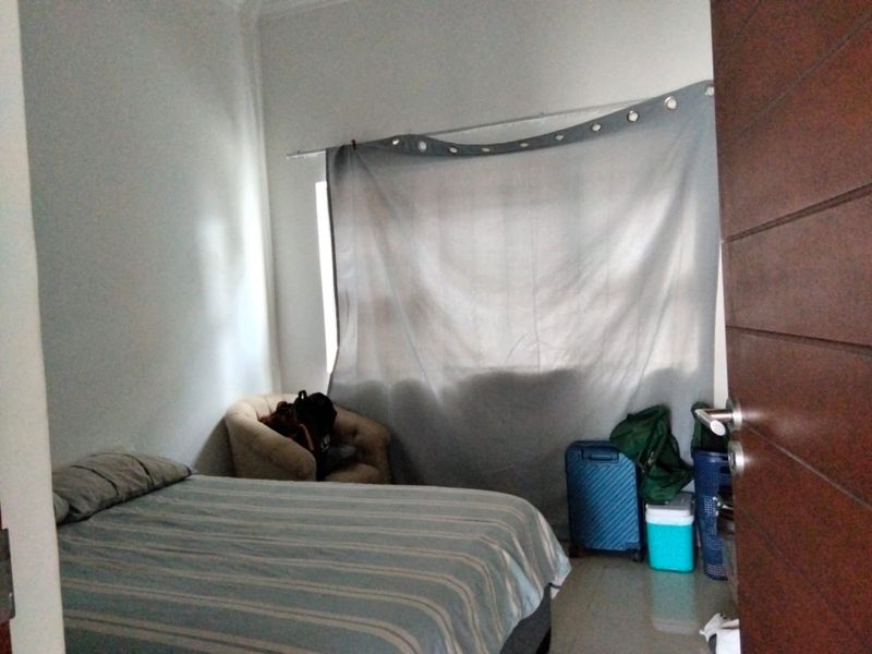 A standard bedroom featuring a window with curtain and a wooden door, providing a functional living space.