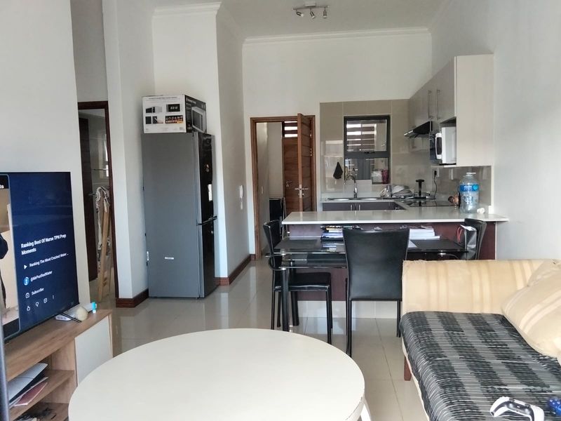 Open plan living and kitchen area featuring tiled floors, modern cabinetry, and a breakfast bar island, creating a functional and connected living space.