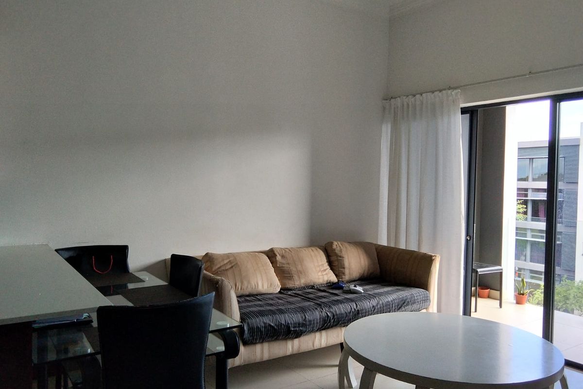 A living room area featuring tiled flooring and a large sliding glass door providing access to an outdoor balcony.