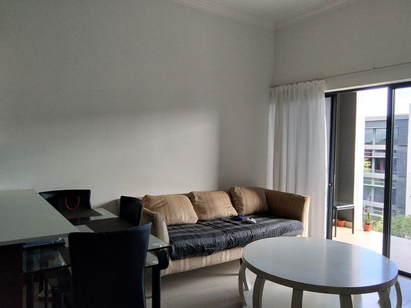 A living room area featuring tiled flooring and a large sliding glass door providing access to an outdoor balcony.