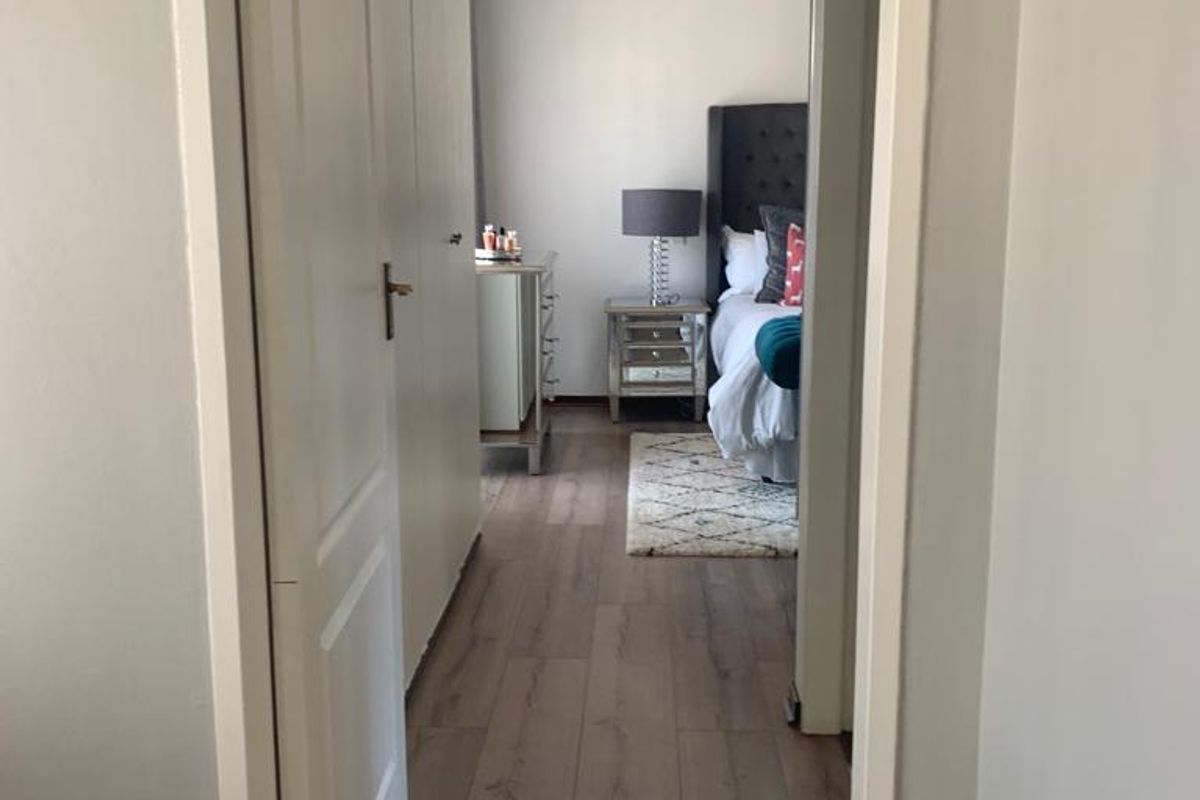 A view through a doorway into a bedroom featuring wood-look laminate flooring and built-in cupboards.