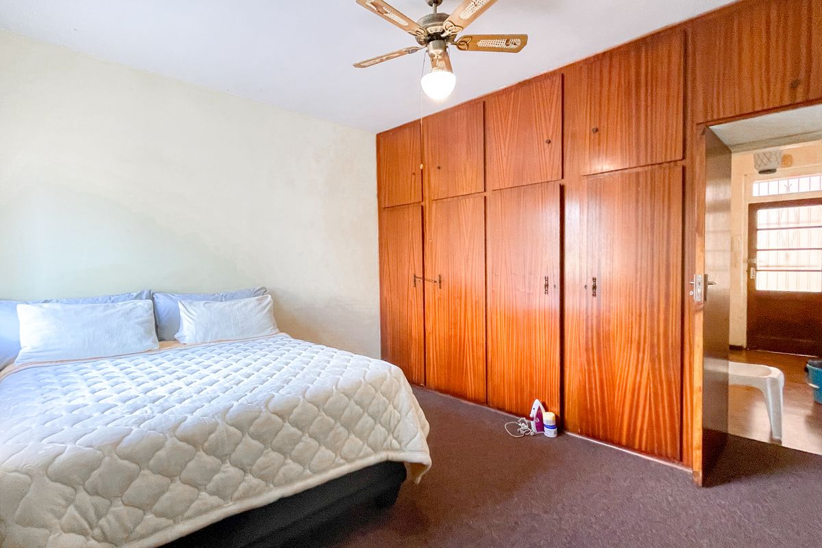 A bedroom featuring extensive built-in wooden cabinetry, a ceiling fan, and carpeted flooring, providing ample storage space.