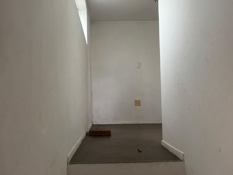 A simple, empty hallway featuring a tiled staircase and plain white walls, providing a functional transition space within the cottage.