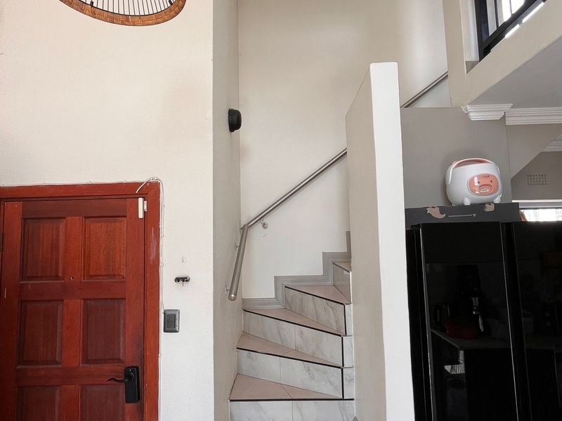 Interior view of an apartment entrance featuring a tiled staircase with a metal handrail and a solid timber front door.