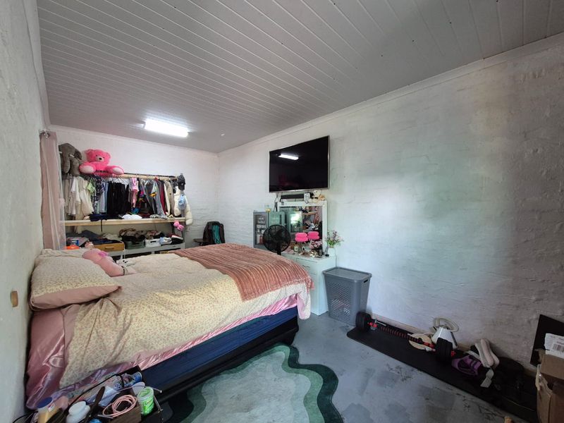 A bedroom featuring painted brick walls and a tongue and groove ceiling, offering a blank canvas for potential renovation and interior design updates.