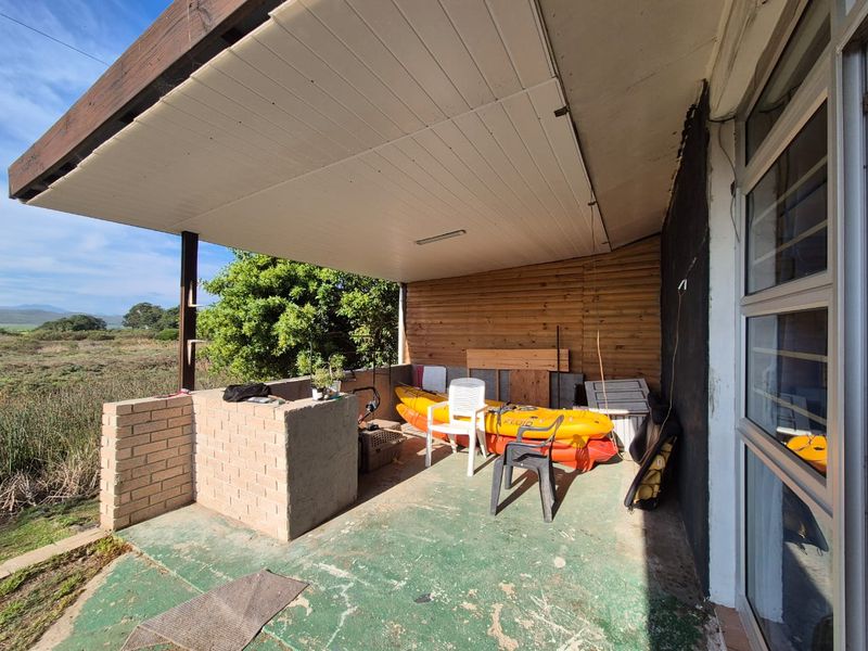 Covered outdoor patio featuring a built-in brick braai, timber wall cladding, and direct access to the garden area.