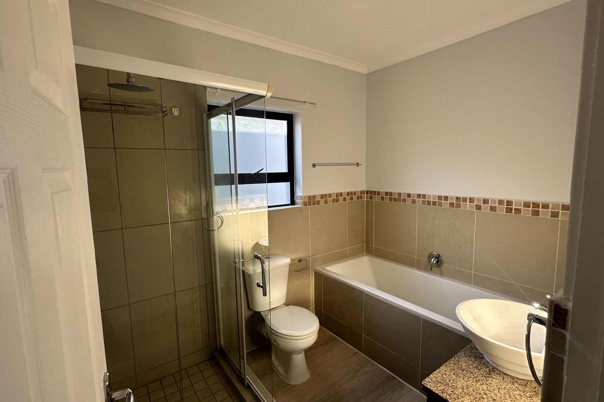 A functional bathroom featuring a glass-enclosed shower, a separate bathtub, a toilet, and a vanity with a vessel sink.