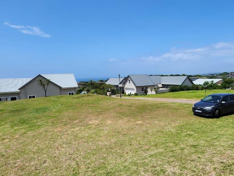 A view of a vacant residential plot featuring a well-maintained grass lawn and access to a paved driveway in a suburban estate setting.