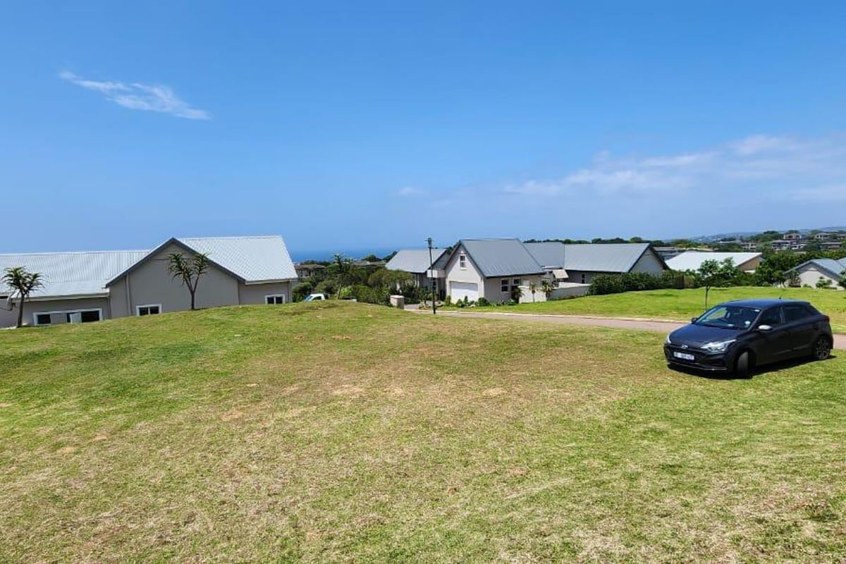 A view of a vacant residential plot featuring a well-maintained grass lawn and access to a paved driveway in a suburban estate setting.