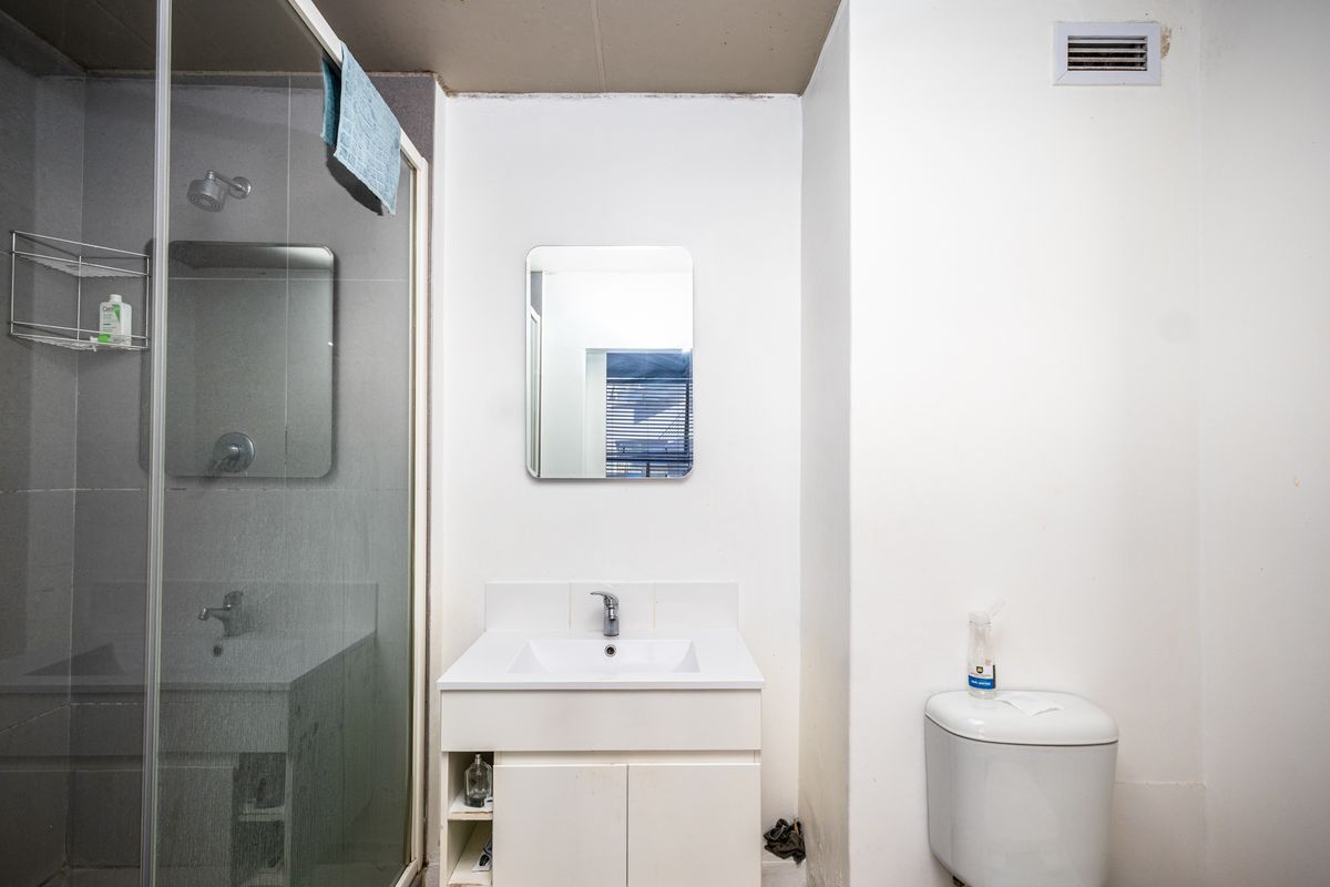A functional bathroom featuring a glass-enclosed shower, a modern vanity with integrated basin, and a standard toilet.