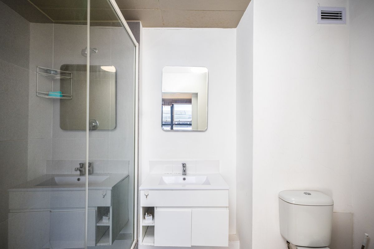 A functional bathroom featuring a glass-enclosed shower, a modern vanity with a basin, and a standard toilet.