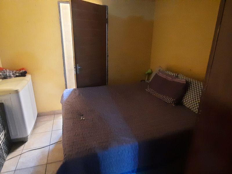 A compact bedroom featuring tiled flooring and yellow wall finishes, requiring cosmetic updates to improve the overall aesthetic and condition.