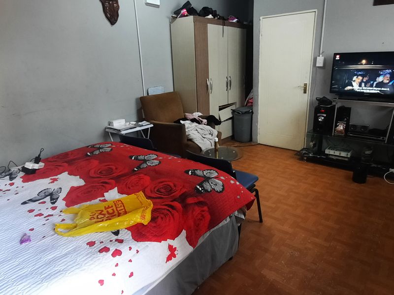 A bedroom featuring a built-in wardrobe and internal door, currently showing signs of wear on the flooring and wall finishes.