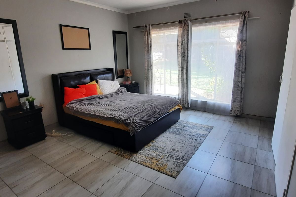 Spacious bedroom featuring tiled flooring, built-in wardrobe storage, and a large sliding glass door providing natural light and garden access.