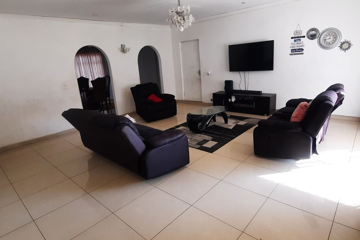 Spacious living room featuring large floor tiles, arched architectural details, and recessed lighting, providing a neutral foundation for modern interior design updates.